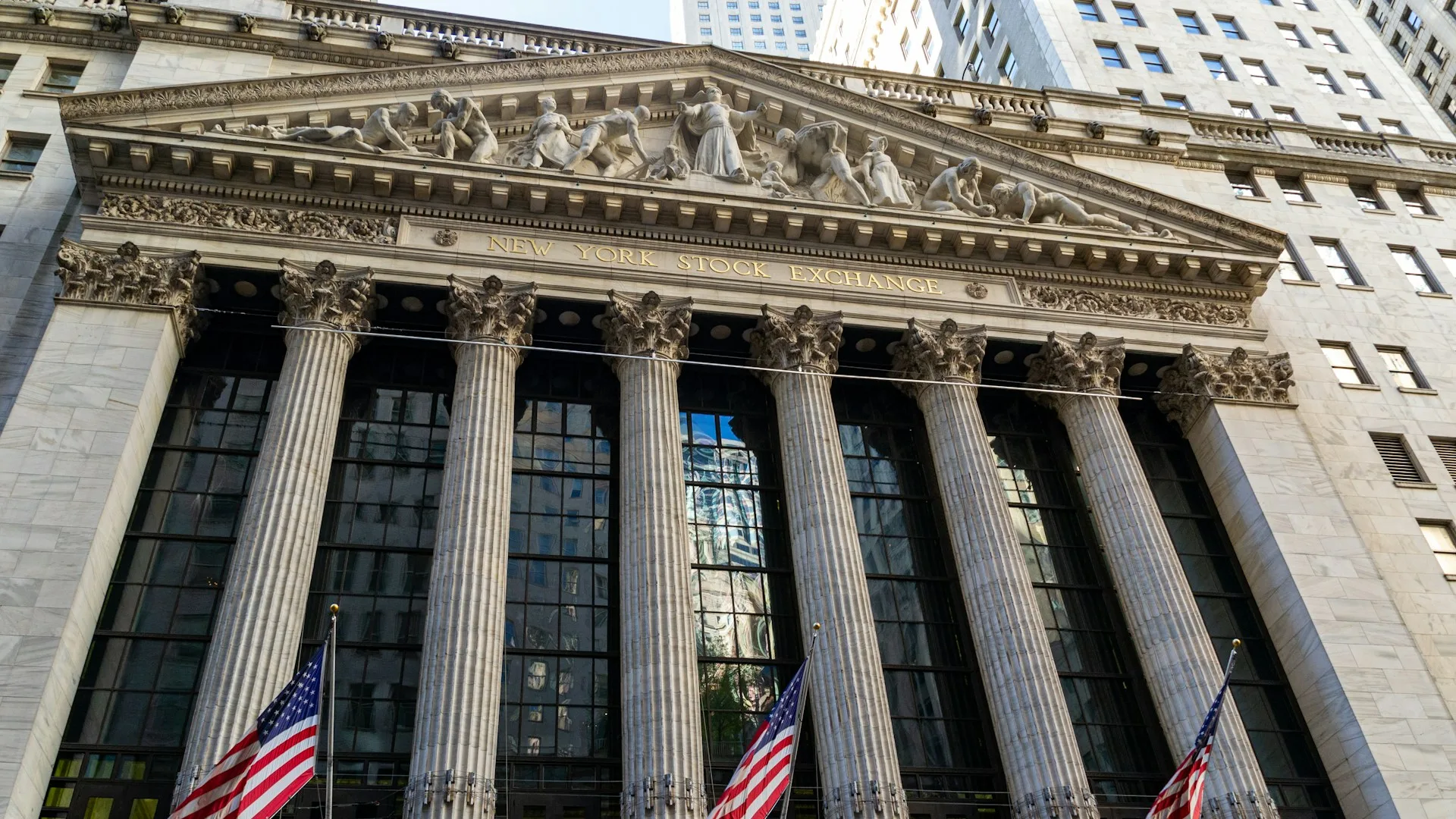 Fachada da Bolsa de Nova York com colunas e bandeiras americanas